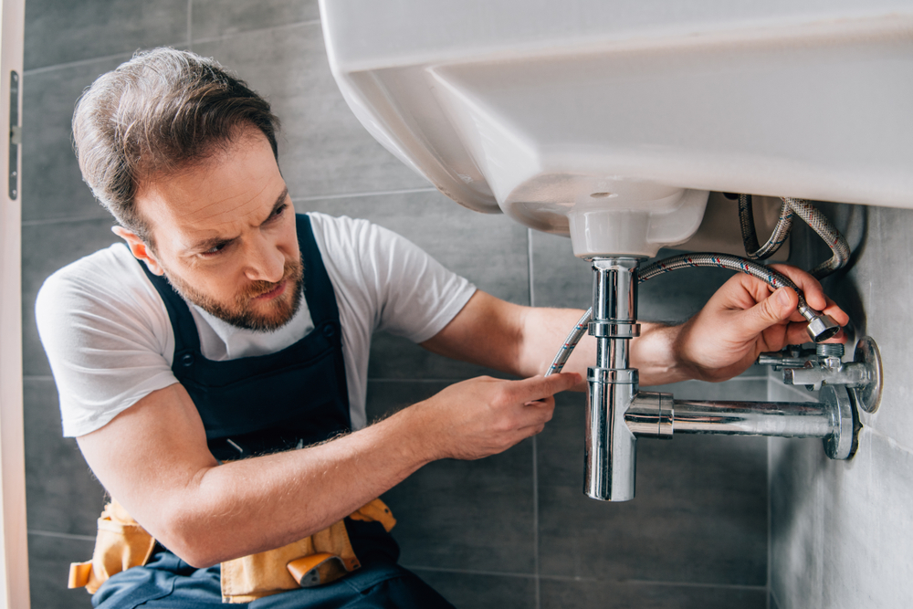 Plumber connecting a flexible hose to a sink trap