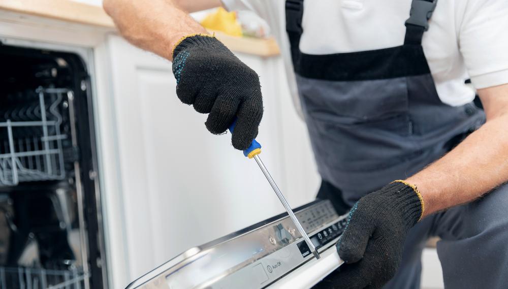 Engineer fitting a dishwasher panel with a screwdriver