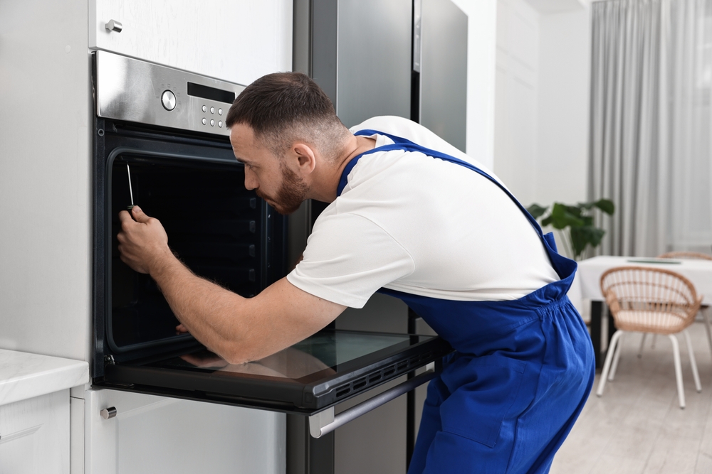 Repairman fixing an oven with a screwdriver