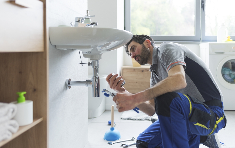 Plumber working on a bathroom sink waste pipe