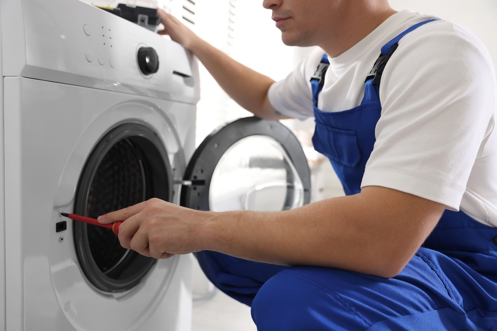 Engineer in uniform repairing a washing machine