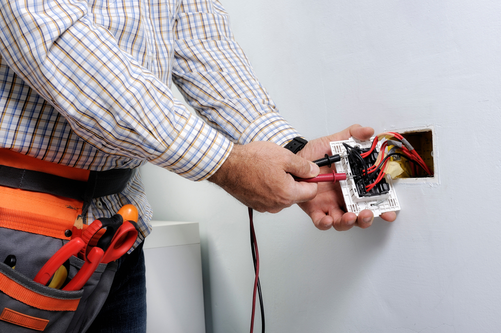 Electrician testing a wall socket with a multimeter